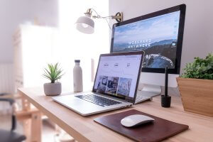 Picture of a laptop and computer at a desk